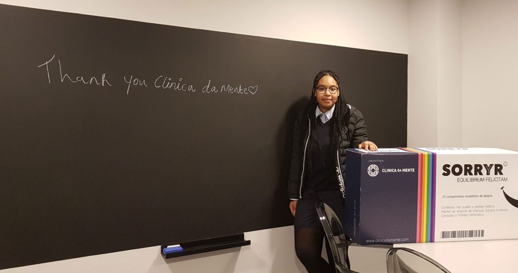 catia manuel junto a uma caixa de sorryr com um quadro de lousa com a frase "obrigada clínica da mente"