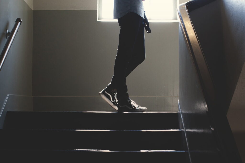 jovem em pé no cimo de umas escadas com uma janela ao fundo