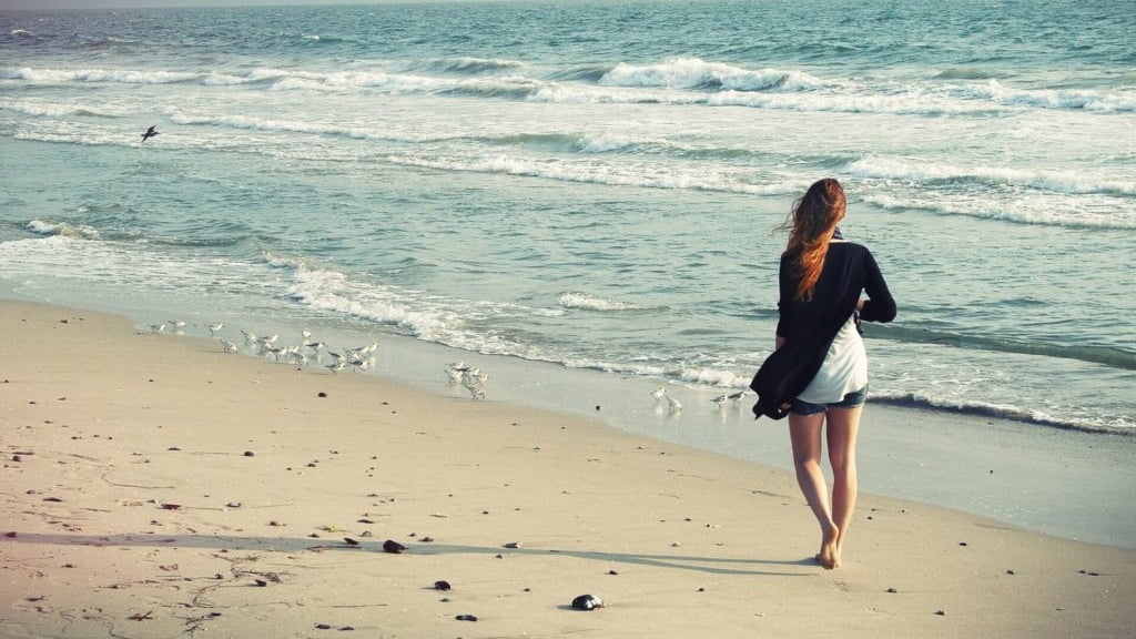 mulher a caminhar na praia